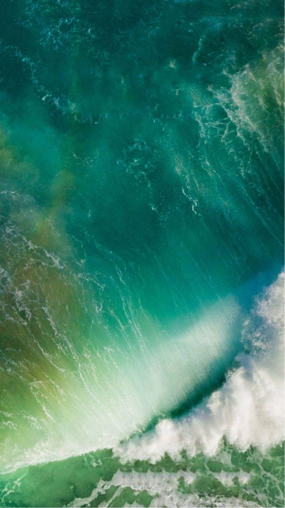 Aerial view of iOS 9 iPhone wallpaper with vibrant teal ocean wave and white sea foam