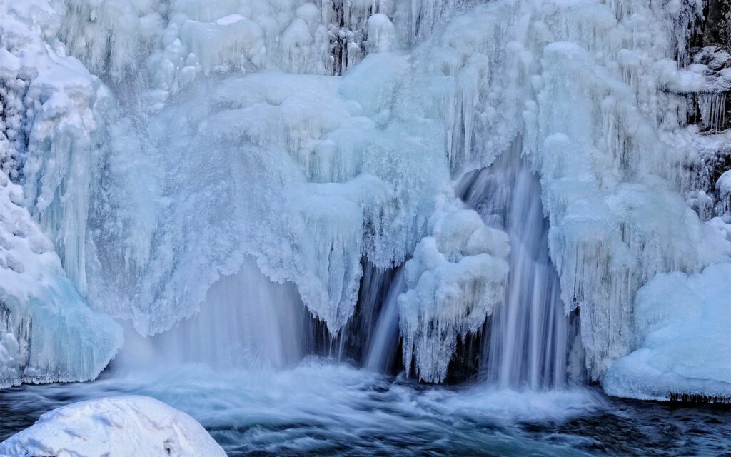 Icy waterfall with crystal-clear streams and shimmering blue frozen formations winter wallpaper background