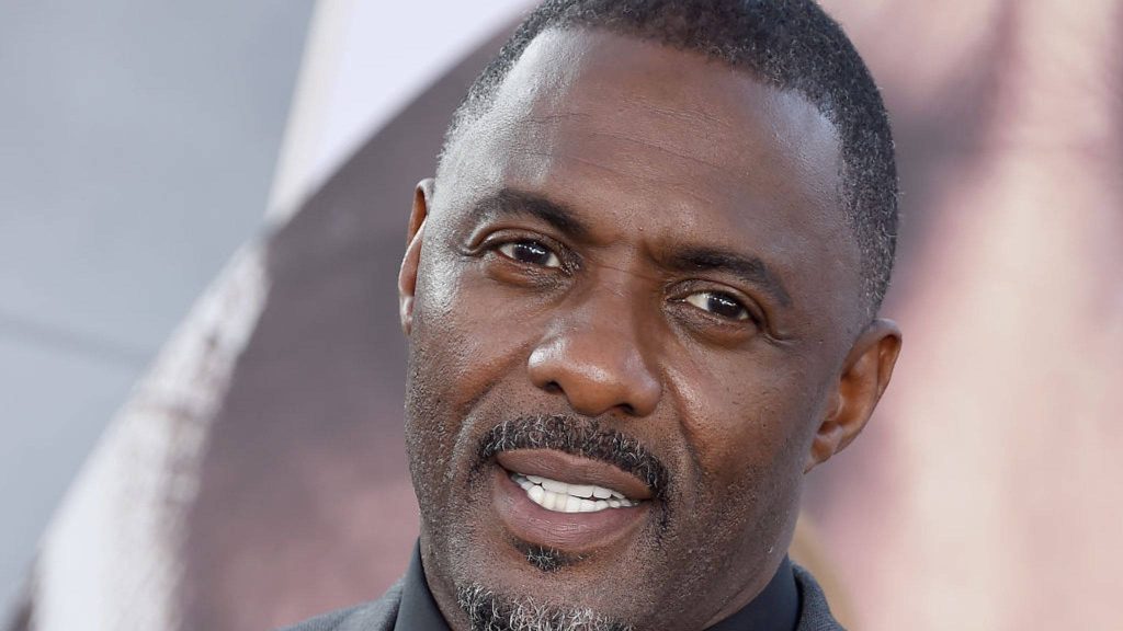 Close-up portrait of Idris Elba smiling in stylish dark attire with professional lighting wallpaper