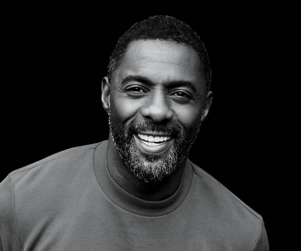 Grayscale portrait of Idris Elba smiling warmly on black background with soft studio lighting wallpaper