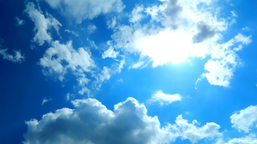 Vibrant 1920x1080 desktop wallpaper of bright blue sky with fluffy white cumulus clouds and sunlight