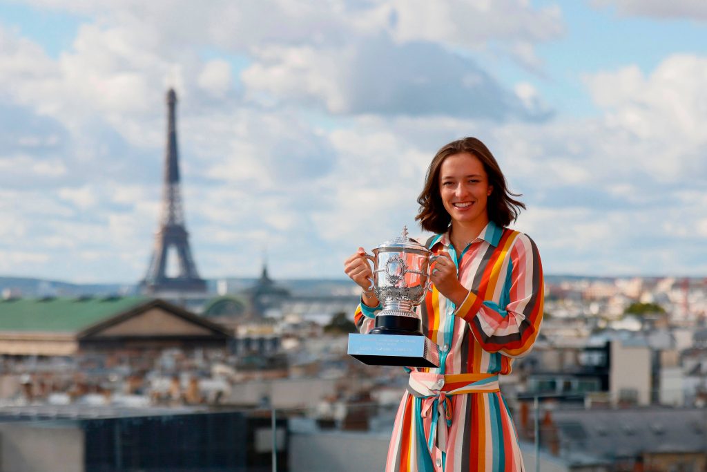 Tennis champion Iga Świątek holds Roland-Garros trophy smiling with Eiffel Tower background Wallpaper