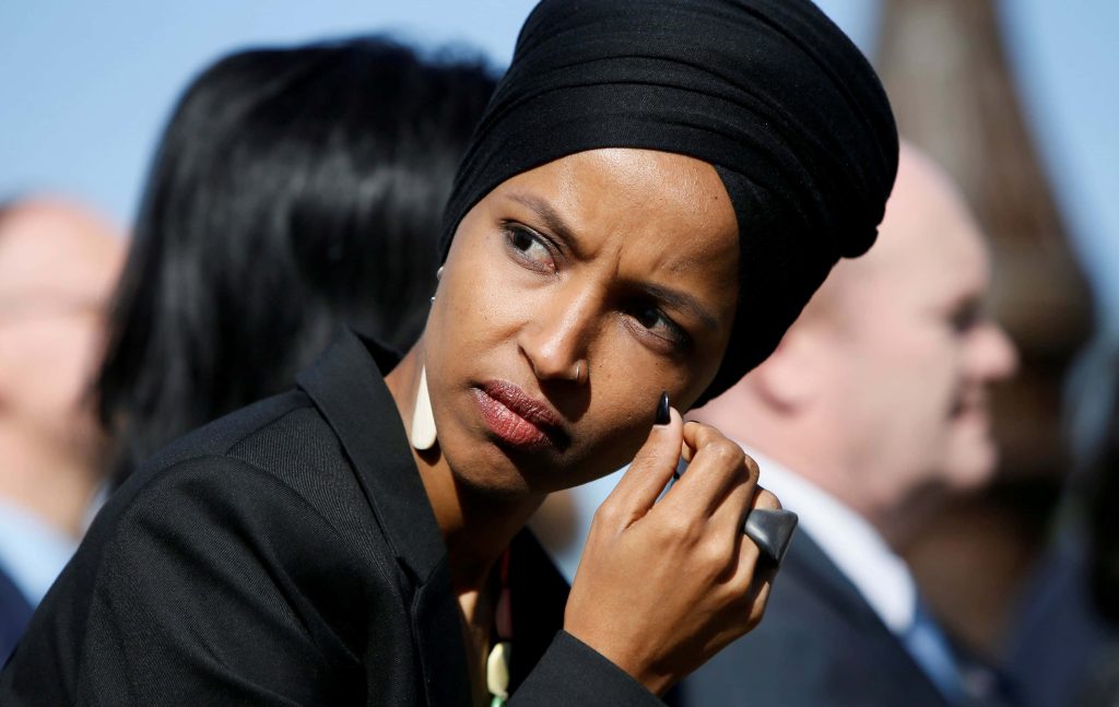 Portrait of U.S. Representative Ilhan Omar in black hijab with focused expression and natural lighting Wallpaper