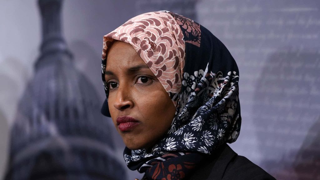 U.S. Representative Ilhan Omar in patterned hijab with contemplative expression Capitol background Wallpaper