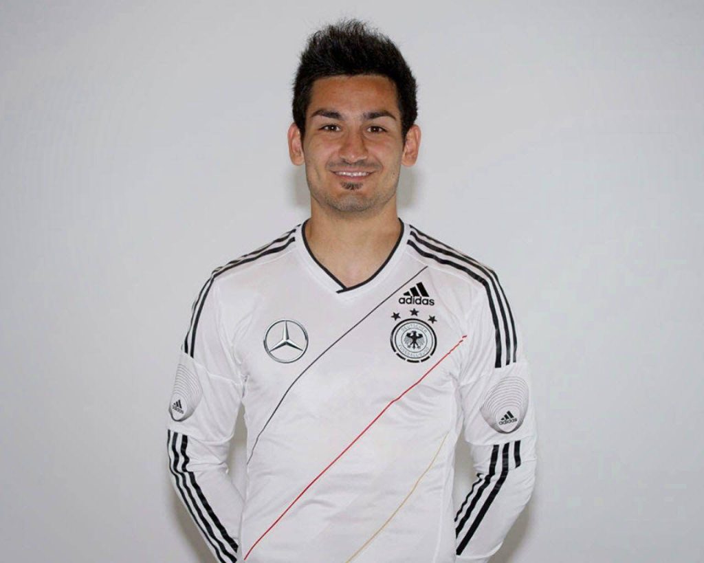 Sharp portrait of footballer İlkay Gündoğan in white Germany national team jersey studio background Wallpaper
