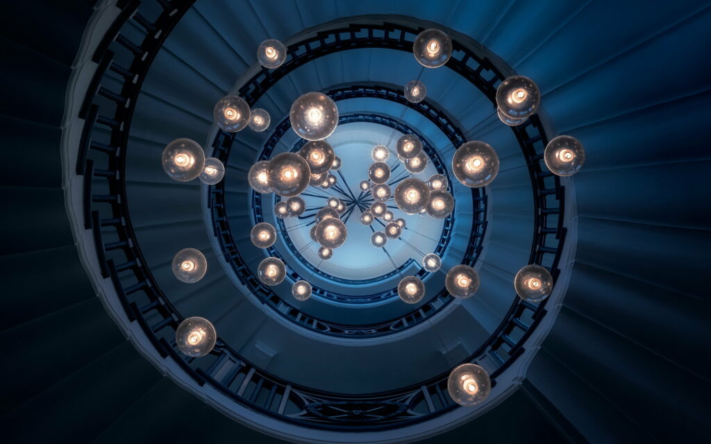 4K wallpaper of spiral staircase with glowing pendant lights and deep blue modern architecture