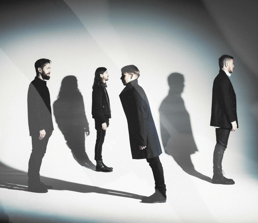 Imagine Dragons band members posing with dramatic shadows on light background 2015 tour poster Wallpaper