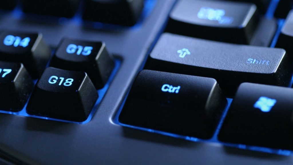 Close-up of backlit gaming keyboard with glowing blue LED and macro G-keys on dark background Wallpaper
