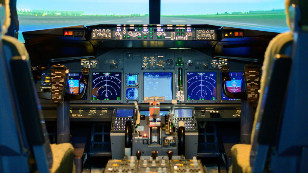 Cockpit view of commercial airplane with illuminated digital displays and detailed control panels Wallpaper