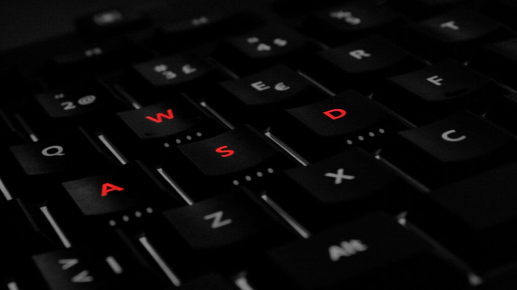 Immersive Gaming Experience: Vibrant Red WASD Keys in Tilted Laptop Wallpaper
