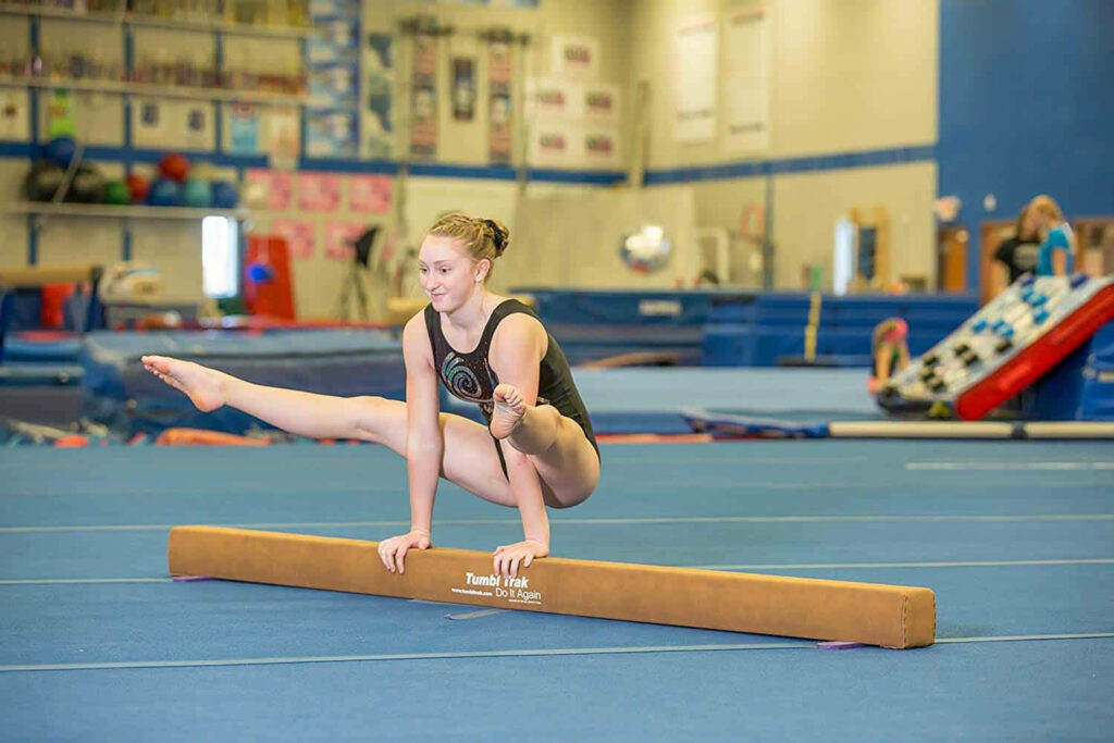 Striking Gymnast Straddle Press on Balance Beam - Wallpaper Background