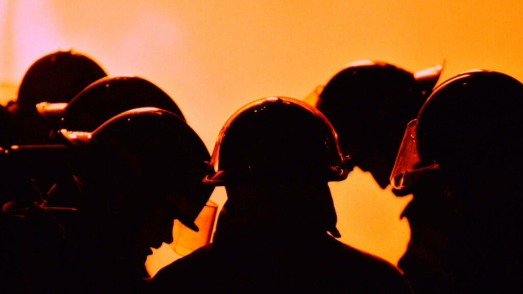 United in Faith: Firefighters Seek Strength and Guidance Amidst Fiery Background Wallpaper