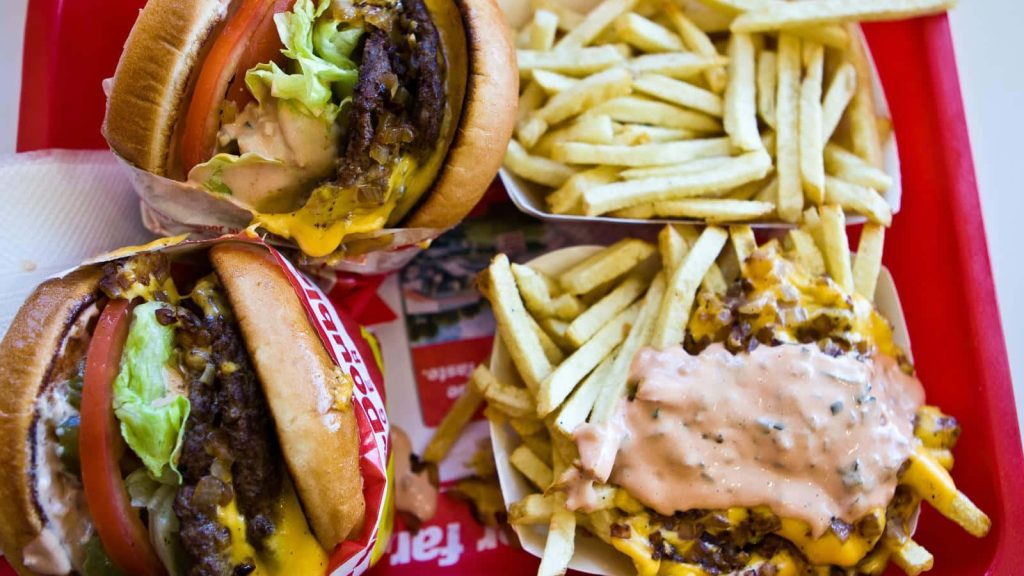 Top-down view of In-N-Out burgers with regular and Animal Style fries on red tray wallpaper