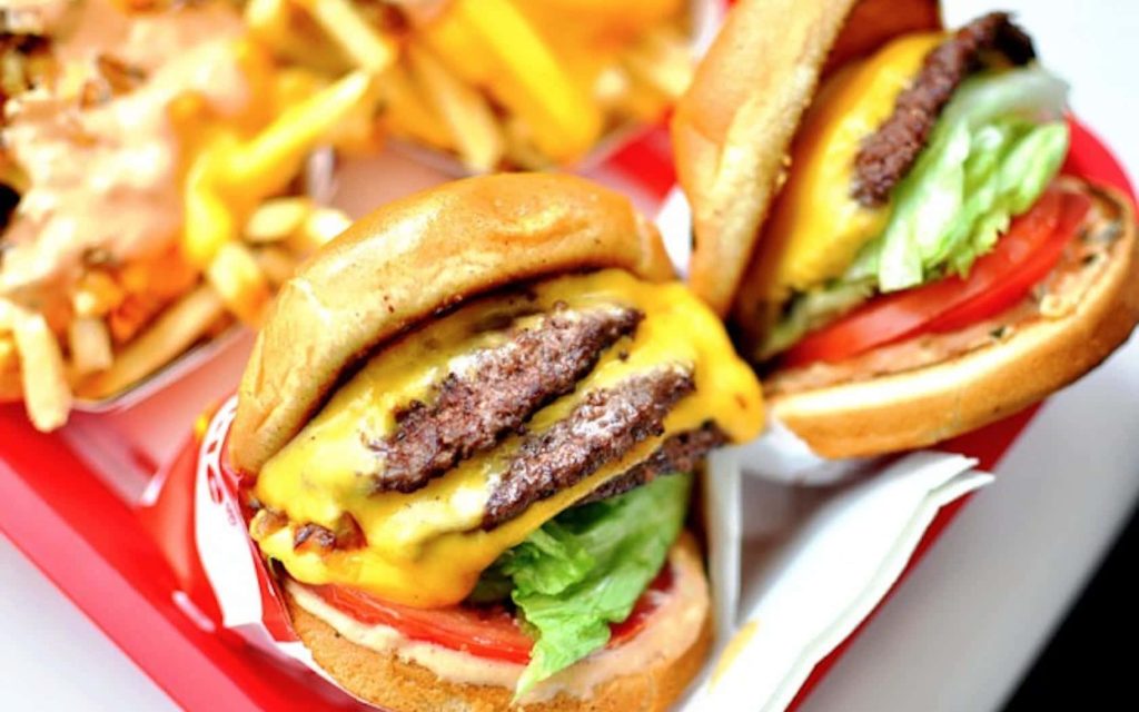 Close-up of a juicy In-N-Out Double-Double cheeseburger with fries on a red tray wallpaper
