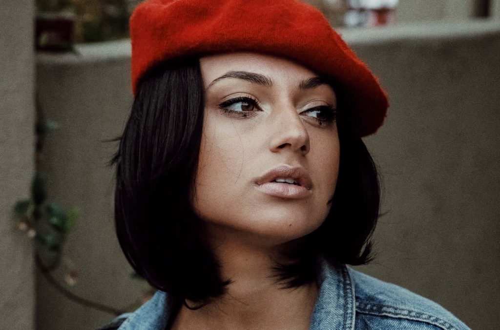 Close-up of Inanna Sarkis in a red beret and denim jacket with moody natural lighting wallpaper
