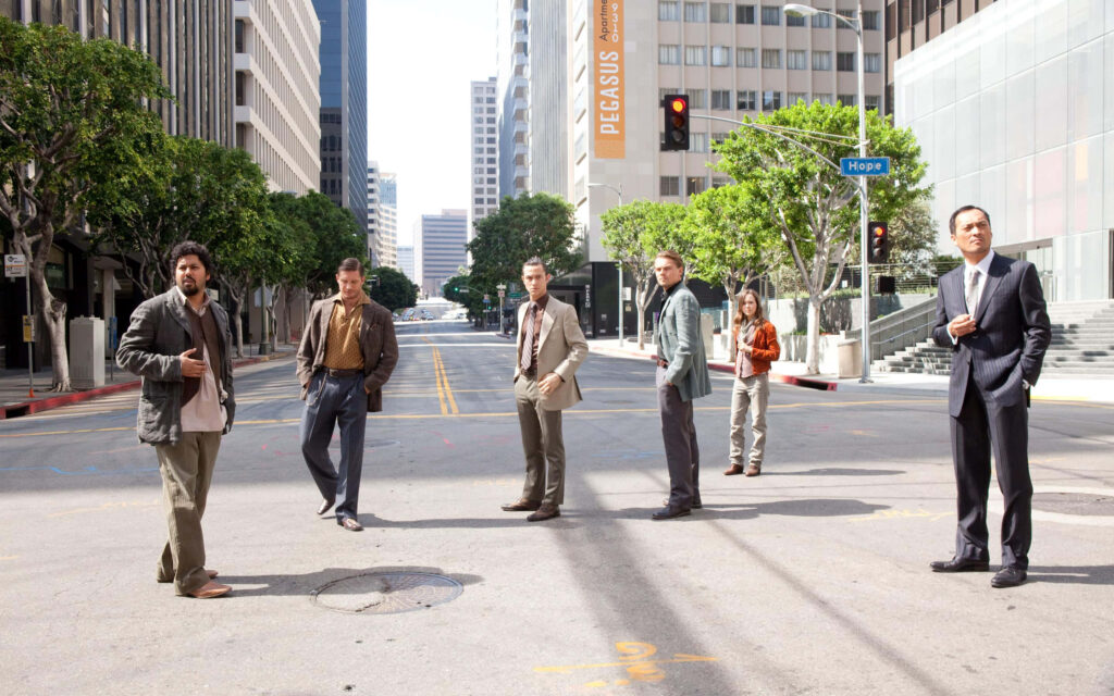 Inception movie characters on city street with tall buildings and greenery dramatic wallpaper background