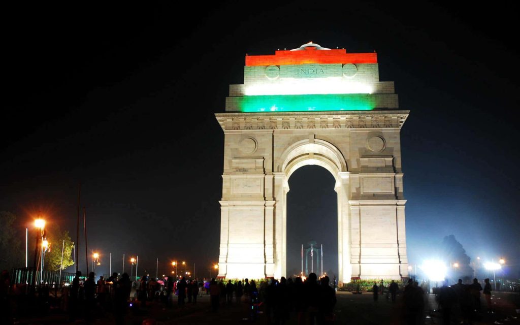 India Gate New Delhi glowing at night with Indian flag colors and visitors silhouette background Wallpaper