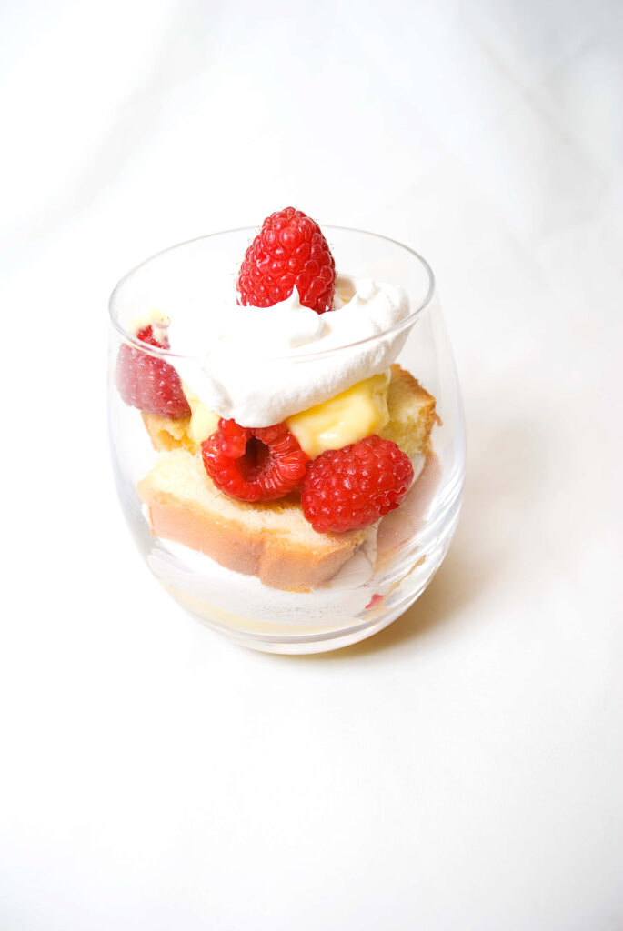 Indulgent Layered Dessert in Glass with Cake, Cream & Raspberries Wallpaper