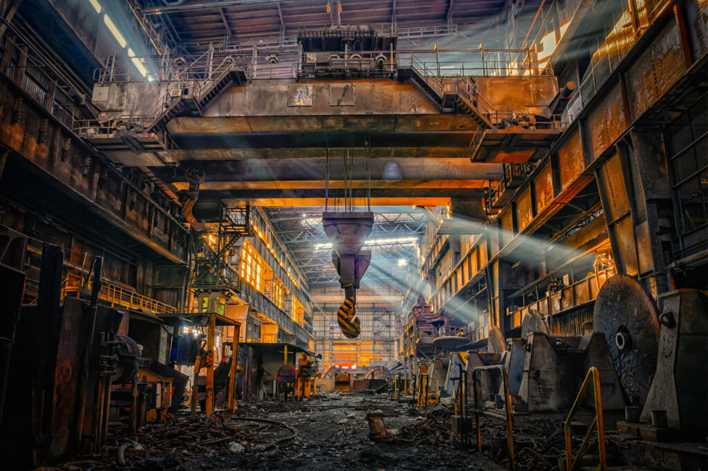 Industrial factory interior with heavy machinery rusted metal and sunlight through high windows Wallpaper