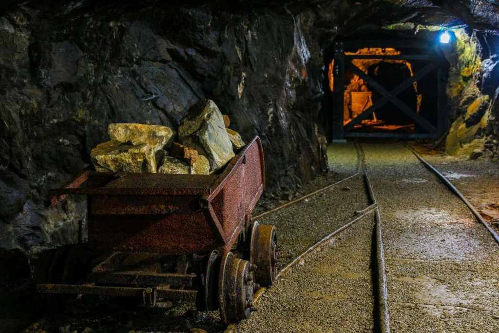 Mining Cart in Dim Goldmine Tunnel: Rustic Industrial Atmosphere Wallpaper