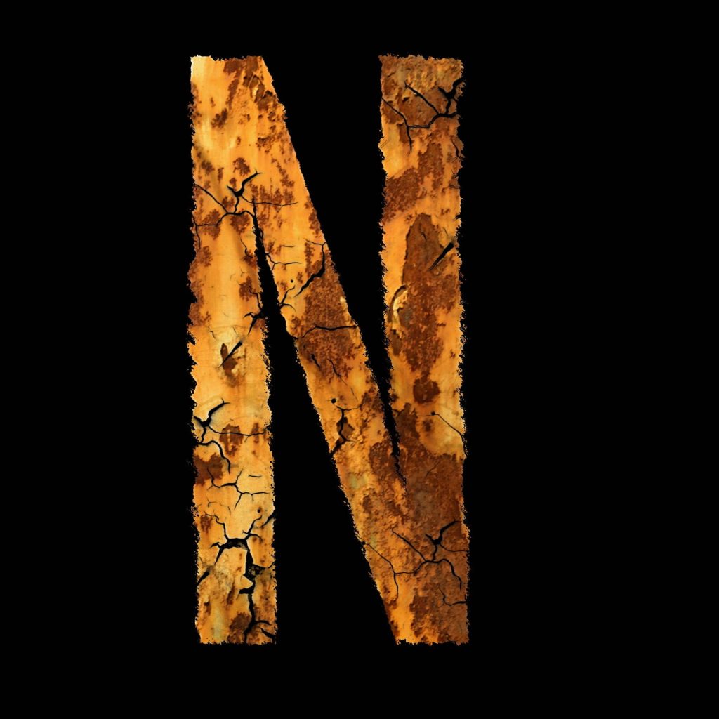 Industrial-style oxidized metal letter N with cracked weathered orange and brown textures on black background wallpaper