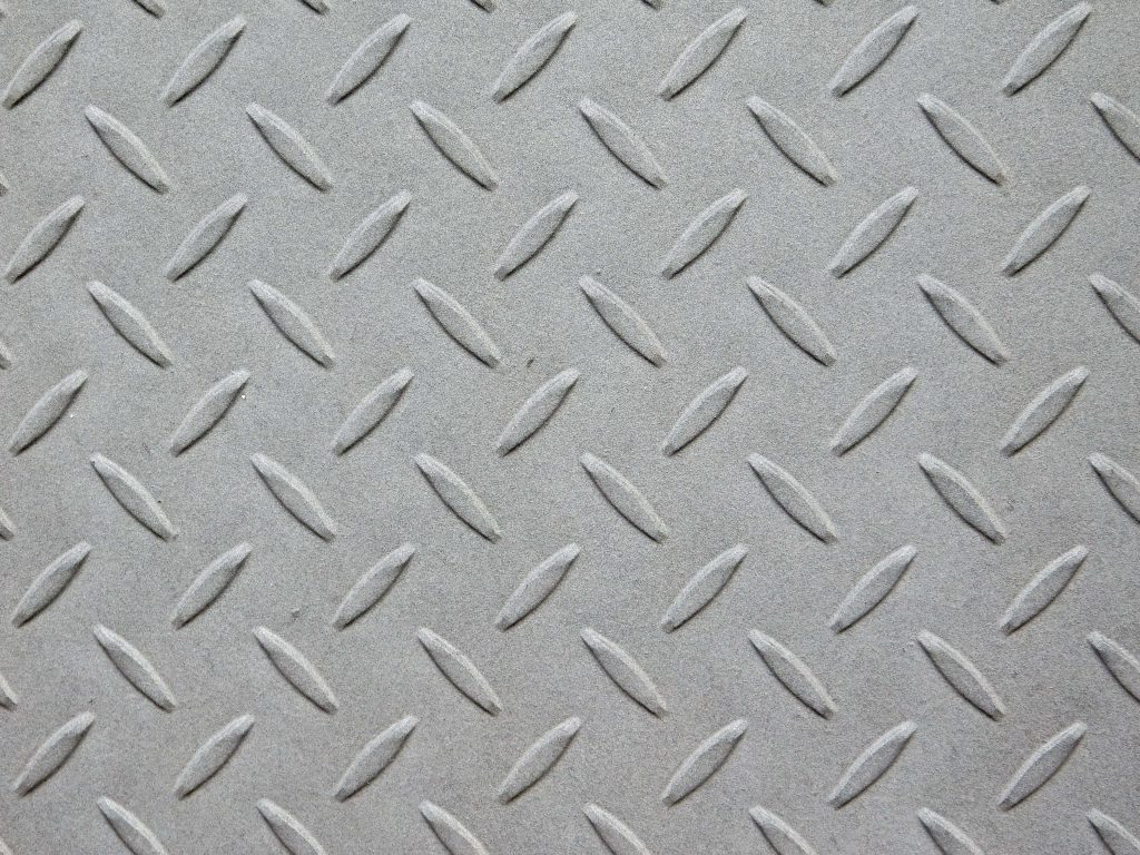 Close-up industrial steel diamond plate wallpaper with raised tread pattern in neutral grey tones