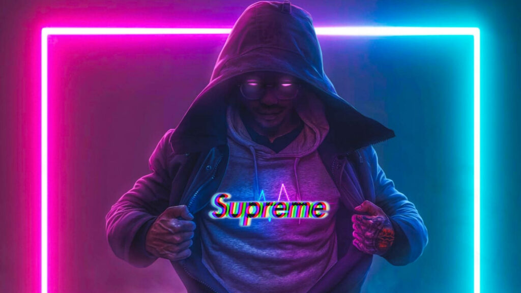 Vividly Luminous: A Stylish Individual Flaunting Supreme Apparel in a Dynamic Neon Setting Wallpaper