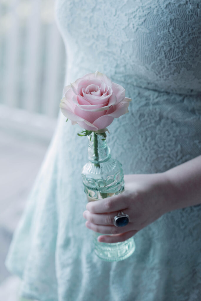 Enchanting Floral Delight: Captivating iPhone Wallpaper focusing on a Woman and her Pink Rose, Encased in Crystal Clear Plastic Bottle