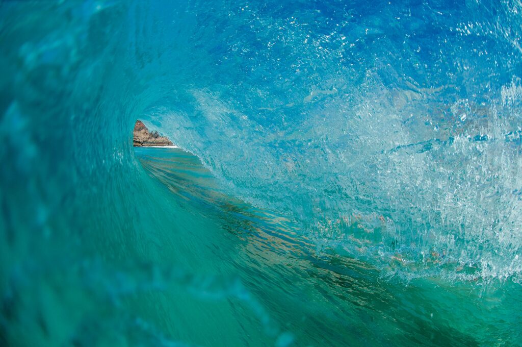 Close-up inside curling ocean wave with blue turquoise hues and sparkling sunlight reflections Wallpaper