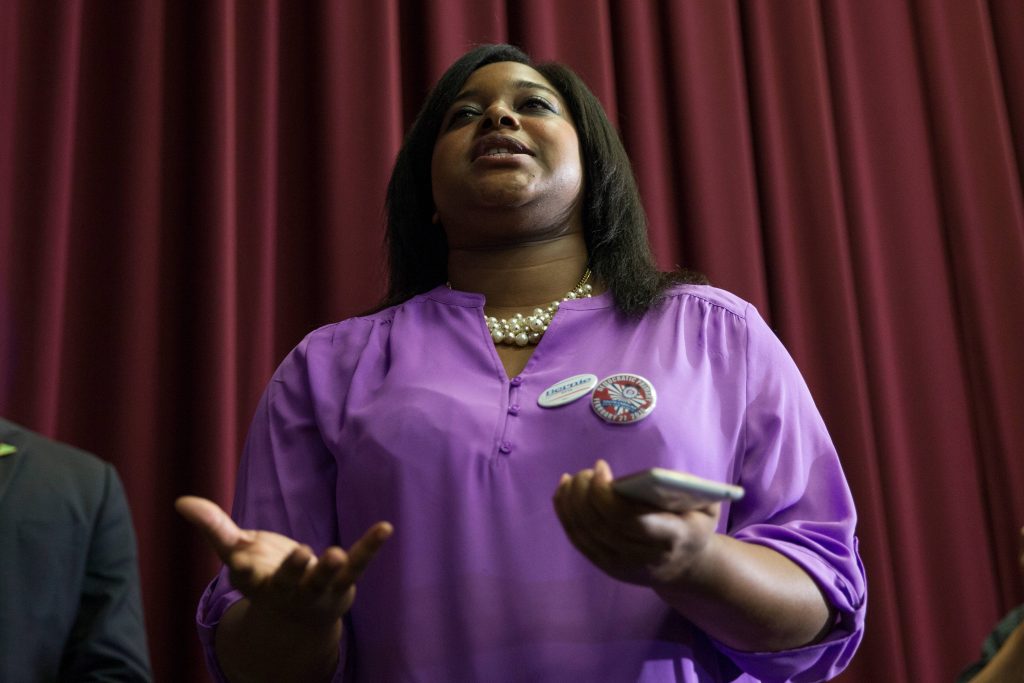 Black woman speaking at political event wearing purple blouse and Bernie 2016 buttons Wallpaper