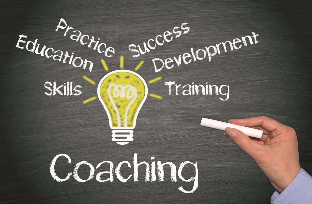 Hand drawing glowing yellow lightbulb on blackboard with coaching education skills keywords background Wallpaper