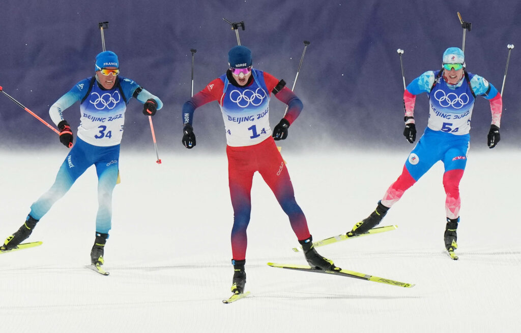 Intense Biathlon Match Wallpaper: Athletes Under Olympic Spotlight