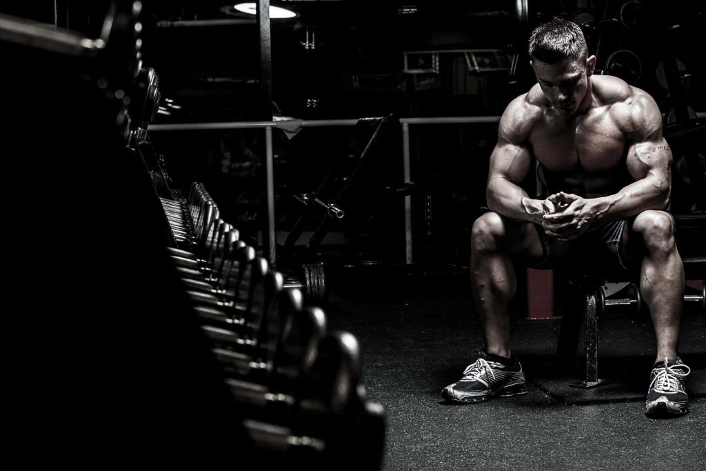 Muscular man resting on bench between sets gym wallpaper intense black and white fitness motivation