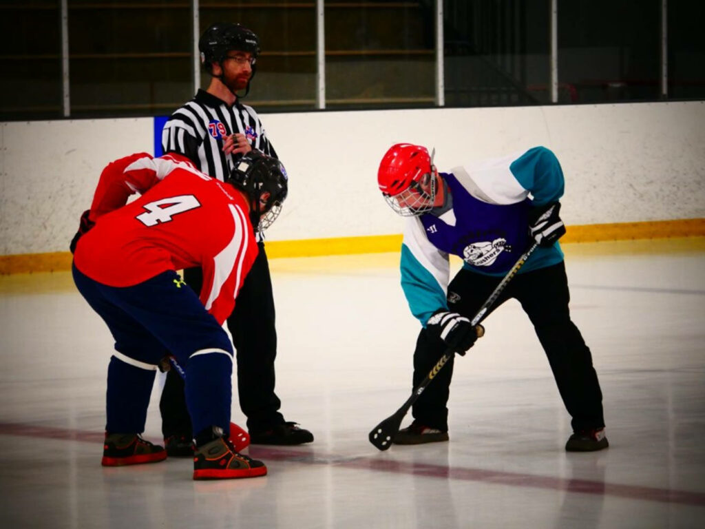 Intense Broomball Game Wallpaper: Blue vs. Red Teams on Ice