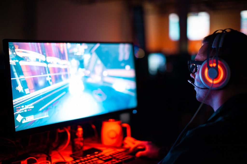 Focused gamer in blue-lit room wearing red headset playing Destiny 2 immersive PC gaming wallpaper
