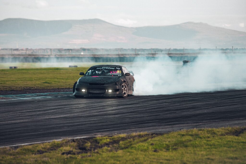 Intense Drift Racing Wallpaper: Car, Smoke & Rolling Hills Scene