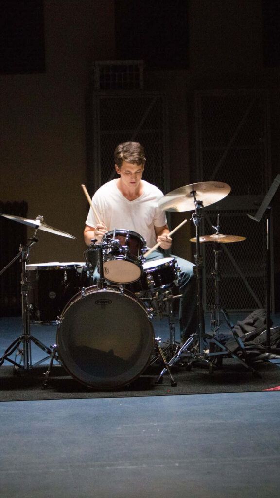 Passionate Drummer in Dim Light: Intense Practice Wallpaper Background