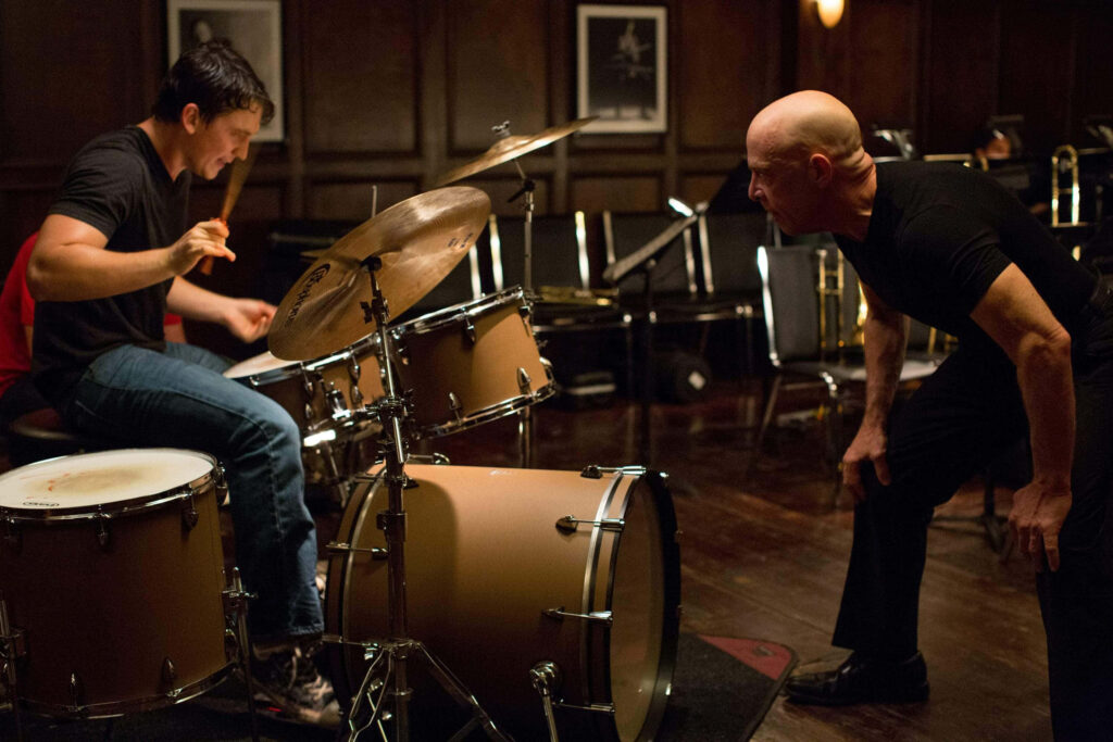Intense Drumming Session: Focused Drummer & Instructor in Action Wallpaper
