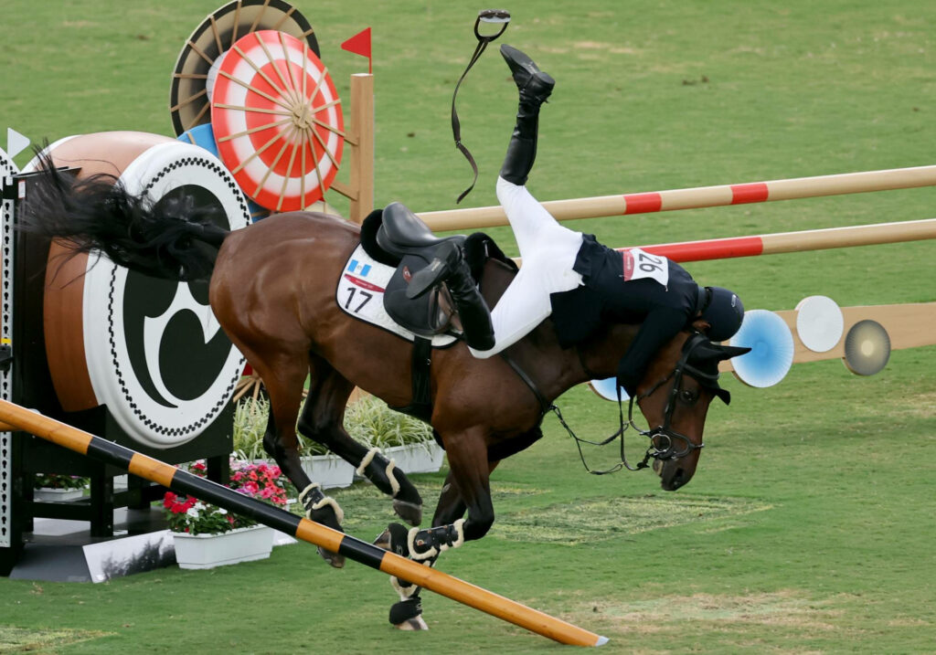 Epic Equestrian Moments: Rider's Narrow Escape in Obstacle Race Wallpaper