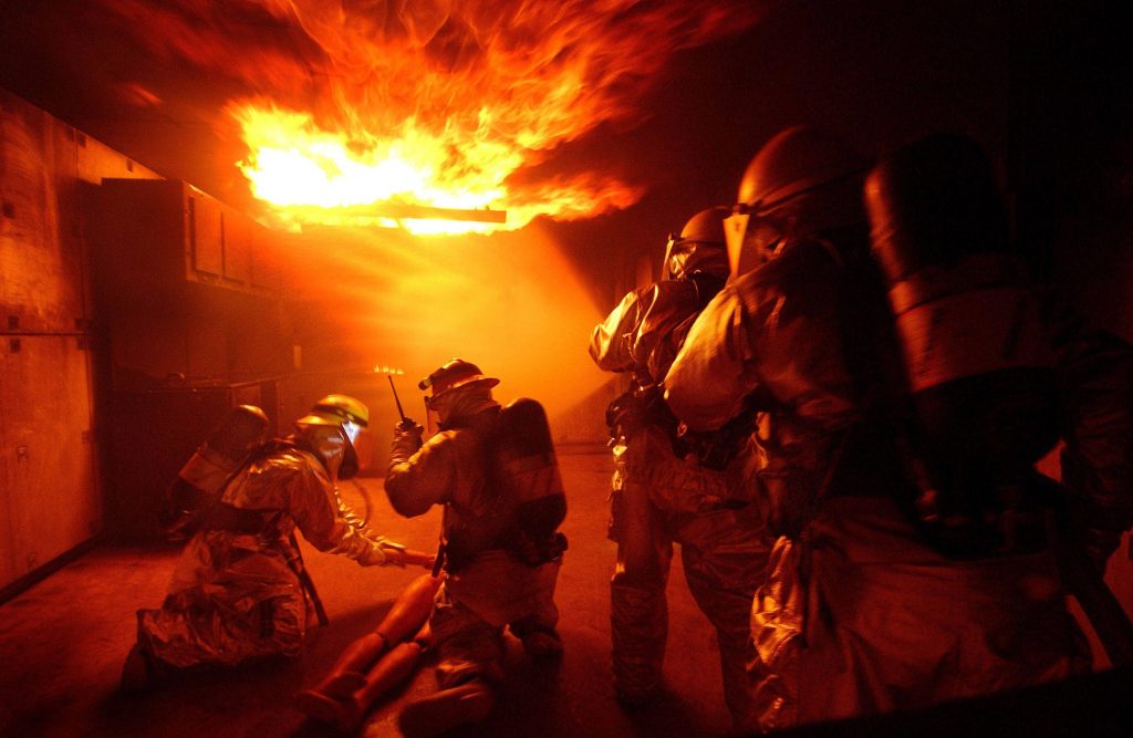 Firefighter training live fire drill with protective gear and SCBA in smoky room flames wallpaper