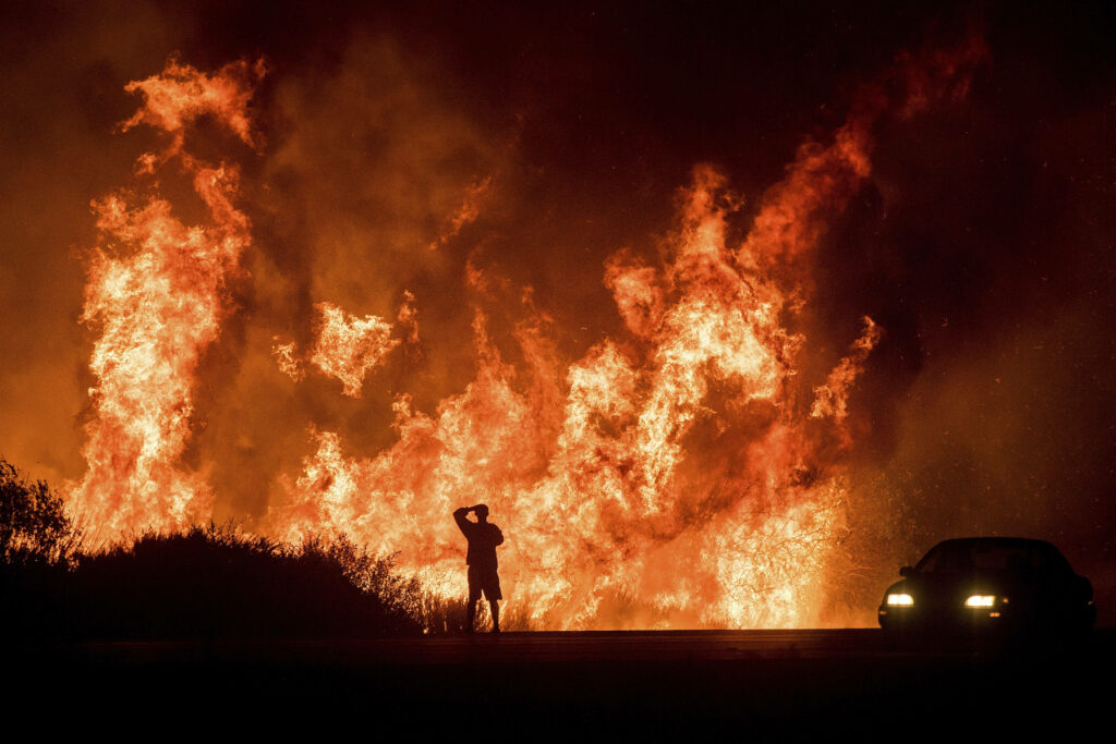 Intensity Unleashed: Man Courageously Confronts Destructive Blaze in Enigmatic Wilderness Wallpaper