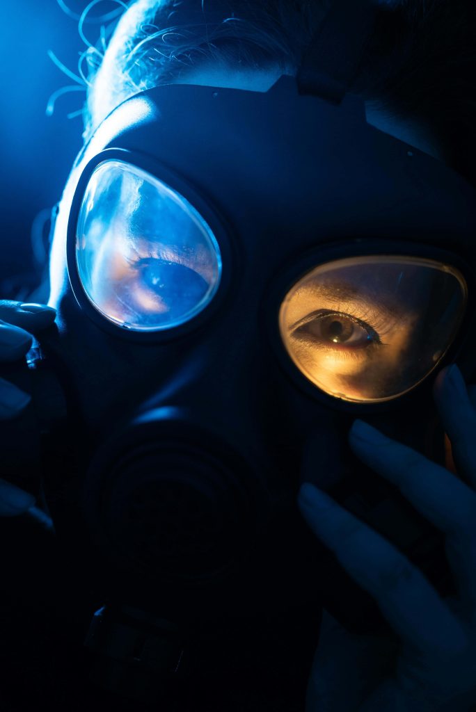 Close-up gas mask portrait with cinematic blue and orange lighting for dystopian wallpaper