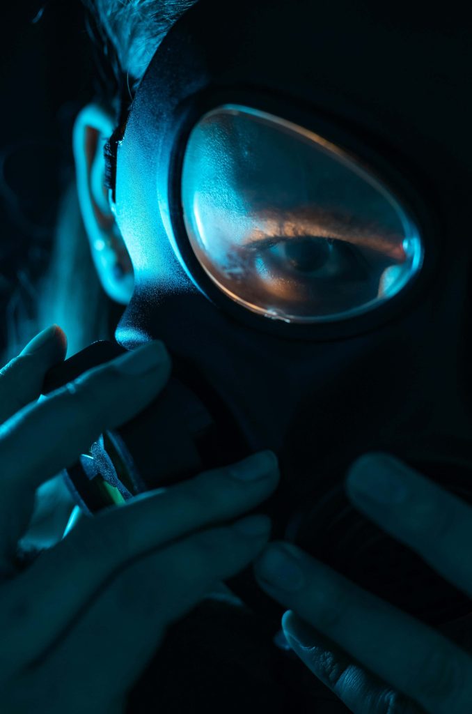 Intense gaze through gas mask with blue rim lighting and deep shadows cinematic wallpaper background