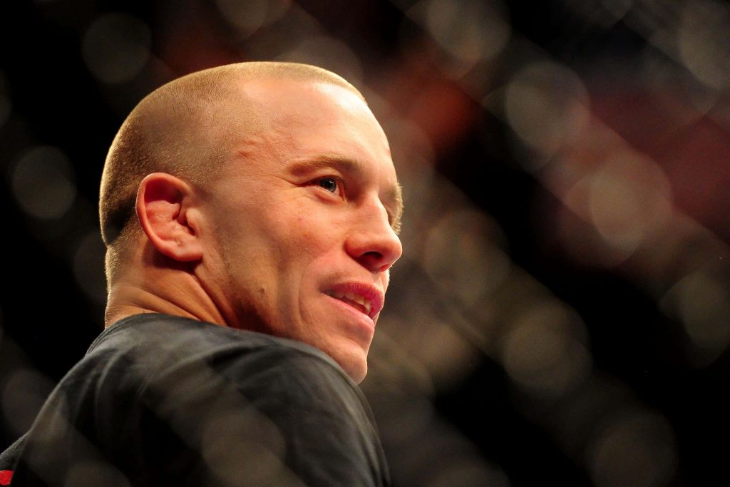 Close-up of MMA legend Georges St-Pierre with intense expression in blurred Octagon background Wallpaper