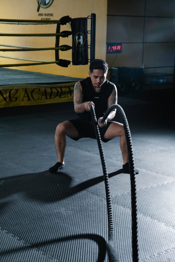 Tattooed athlete training with battle ropes at Hero Fighting Academy intense gym motivation wallpaper