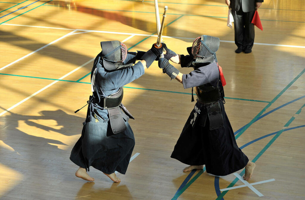 Intense Kendo Battle Wallpaper: Dynamic Duel in Indoor Dojo