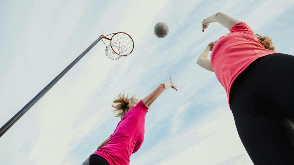 Intense Netball Moment Wallpaper: Players Jumping Under Clear Sky