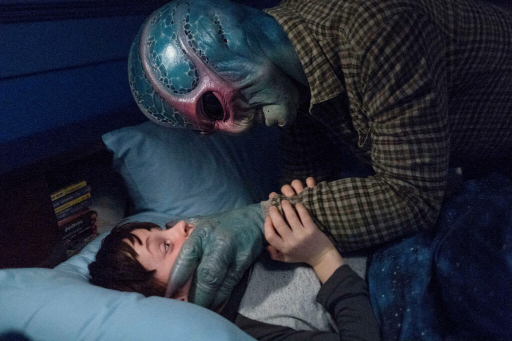 Suspenseful Scene: Resident Alien's Intense Moment in Dim Bedroom Wallpaper