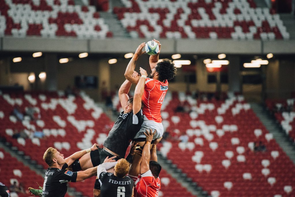 Professional rugby lineout action with players lifting teammate to catch Gilbert ball mid-air Wallpaper