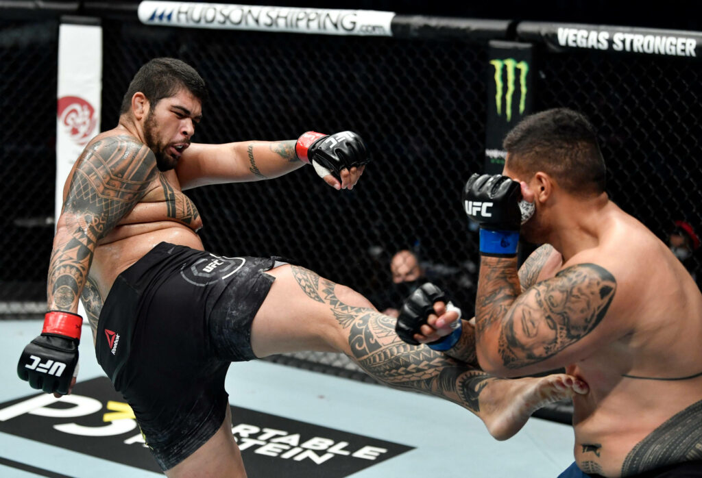 Two tattooed UFC fighters exchange fierce blows inside the octagon intense MMA action wallpaper